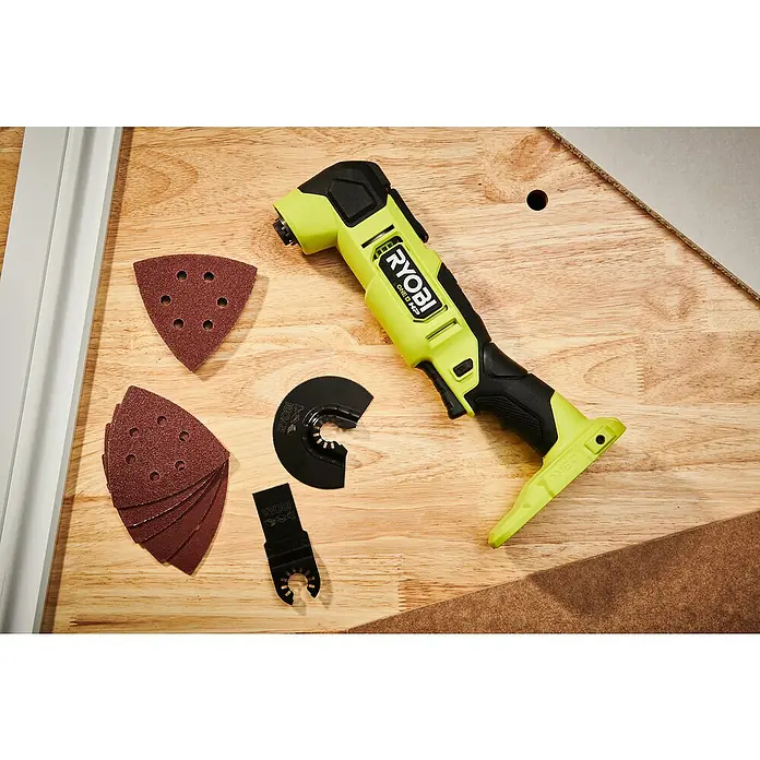 Ryobi ONE+HP Akku-Multifunktionswerkzeug RMT18X-0 - 18 V, Ohne Akku - Ryobi Multifunktionswerkzeug mit Schleifpapier und Zubehör auf einer Holzoberfläche.
