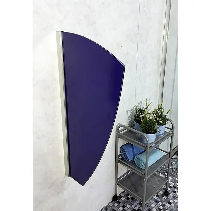 GEO Urinal-Trennwand Segel - 50 x 90 cm, Glas, Blau - Ein blauer, halbkreisförmiger Spiegel mit Metallrahmen hängt an einer Marmorwand in einem Badezimmer. Ein Rollwagen mit Handtüchern steht daneben.