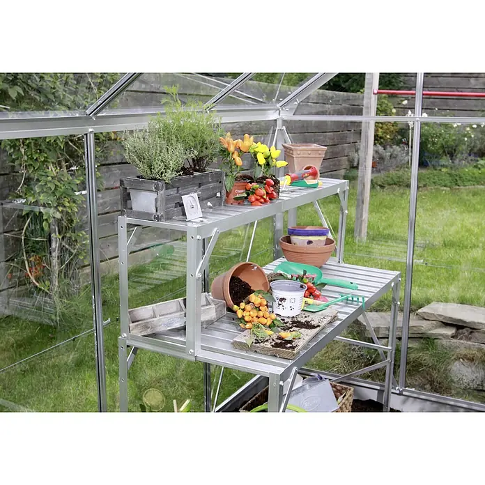 Vitavia Gewächshaus Zeus 15700 Plus - Außenmaß inkl. Dachüberstand (B x T): 256 x 614 cm, 16 mm, Aluminium - Eine Gartenwerkbank aus Aluminium mit zwei Ebenen, auf denen Pflanzen, Töpfe und Gartengeräte arrangiert sind. Ideal für Gewächshäuser.