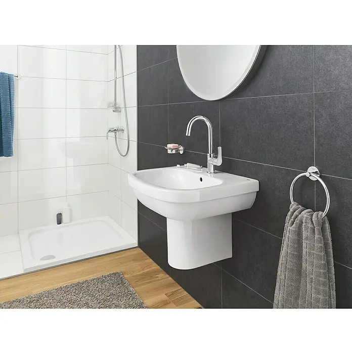 Grohe Essentials Handtuchring - Chrom, Glänzend - Bild eines modernen Badezimmers mit einem weißen Waschbecken mit Armatur und Handtuchring an einer dunklen Wand.