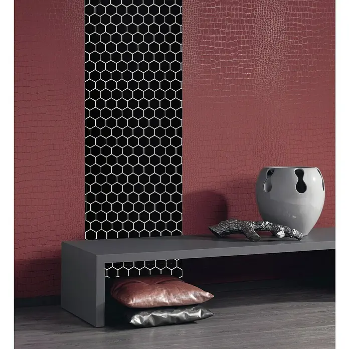 Mosaikfliese Hexagon Uni HX 090 - 32,5 x 28,1 cm, Schwarz, Glänzend - Ein modernes Wohnzimmer mit einer grauen Kommode, dekorativen Kissen und einer auffälligen Wandgestaltung in Rot und Schwarz mit Wabenmuster.