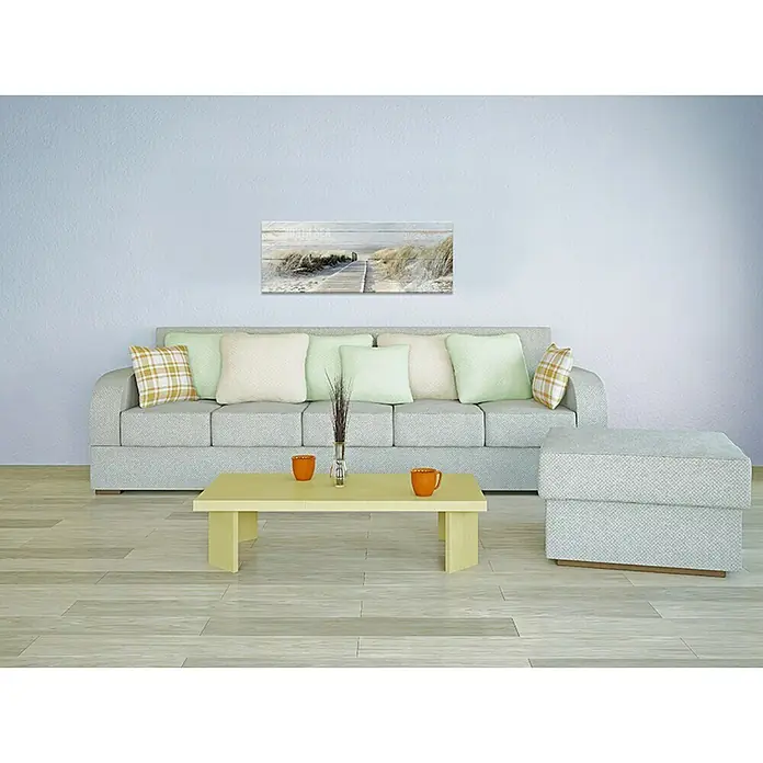 ProArt Type Hype Leinwandbild - Seeblick III, B x H: 80 x 30 cm - Eine moderne Wohnzimmer-Szene mit einem grauen Sofa, hellgelbem Couchtisch und einem Wandkunstwerk mit Strandmotiven.