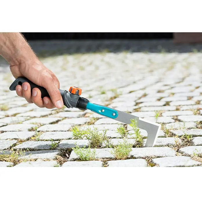 Gardena Combisystem Fugenkratzer - Edelstahl - Eine Hand hält ein Gardena Fugenmesser zum Entfernen von Unkraut zwischen Pflastersteinen.