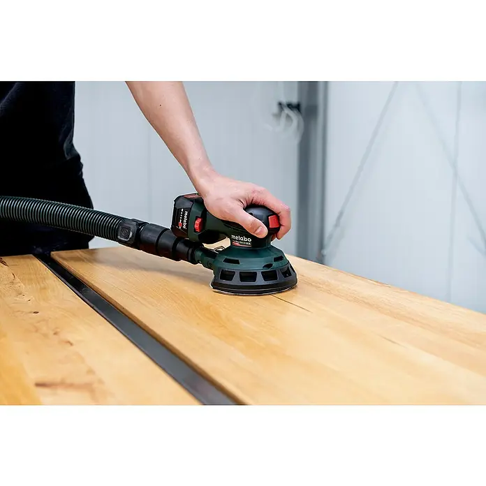 Metabo Akku-Exzenterschleifer PowerMaxx SXA 12-125 BL - 12 V, Ohne Akku - Nahaufnahme eines Akku-Exzenterschleifers Metabo SXA 18 LTX 125 BL, der auf einer Holzoberfläche verwendet wird.