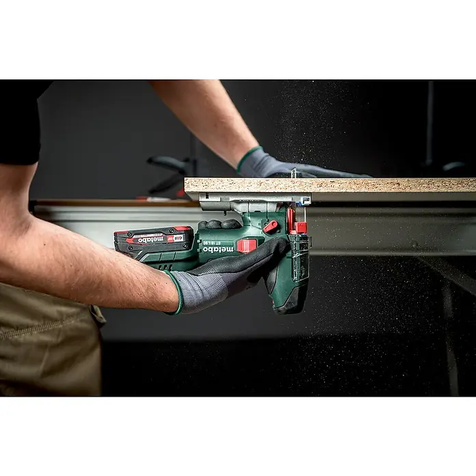 Metabo CAS 18V Akku-Pendelhubstichsäge ST 18 L 90 - 18 V, Ohne Akku, Leerlaufhubzahl: 750 /min - 3.000 /min - Ein Mann sägt ein Holzbrett mit einer Metabo Stichsäge, Späne fliegen. Die Akku-Stichsäge ST 18 LTX 100 ist ein leistungsstarkes Werkzeug.