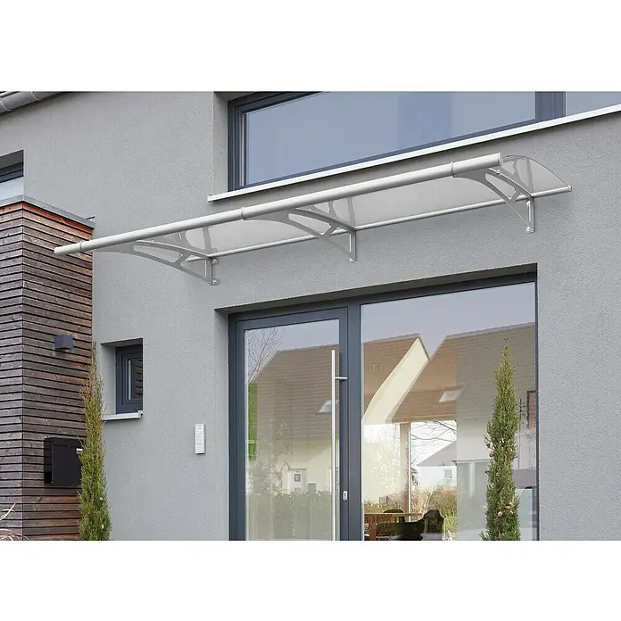 Gutta Pultvordach PT/L - 190 x 95 x 17 cm, Edelstahl, Farbe Dach: Klar - Graue Hausfassade mit einer modernen, transparenten Haustürüberdachung, die vor Wettereinflüssen schützt und das Gebäude optisch aufwertet.