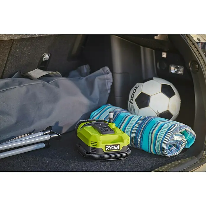 Ryobi ONE+ Akku-Kompressor RMI18-0 - 18 V, 11 bar - Nahaufnahme einer Ryobi-Luftpumpe im Kofferraum eines Autos, umgeben von Strandutensilien.