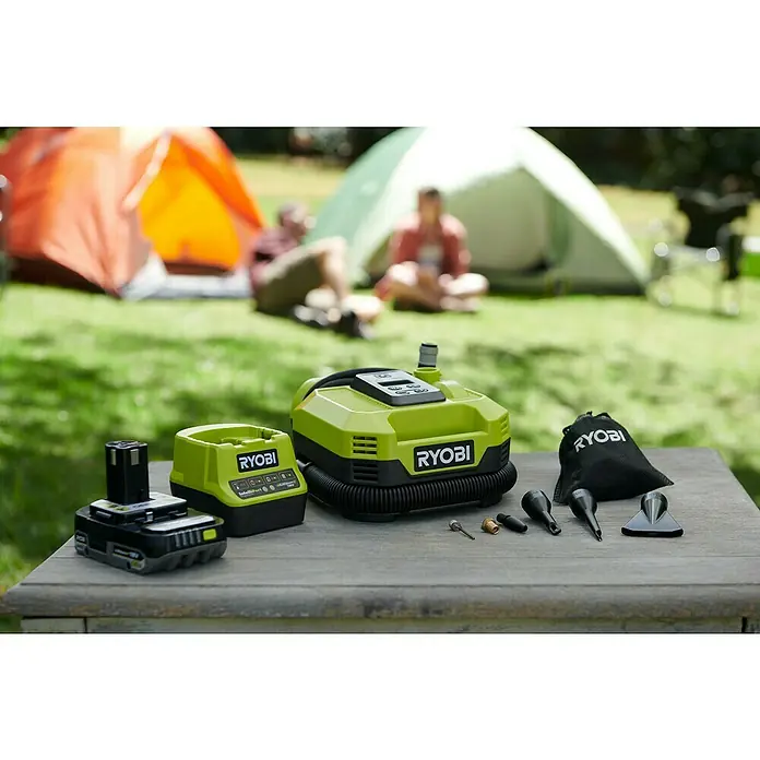 Ryobi ONE+ Akku-Kompressor RMI18-0 - 18 V, 11 bar - Ryobi-Luftpumpe mit Akku, Ladegerät, Tasche und Zubehör auf einem Holztisch im Freien. Ideal zum Aufpumpen von Luftmatratzen beim Camping.