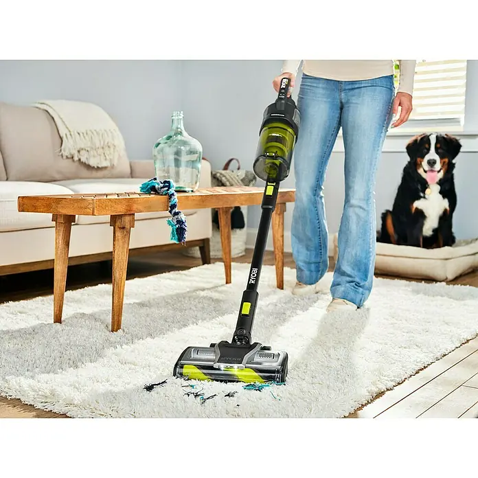 Ryobi ONE+ Akku-Staubsauger RASV18BL-0 - 18 V, Ohne Akku, Behältervolumen: 1.000 ml - Der RYOBI Akku-Staubsauger entfernt mühelos Schmutz von einem weißen Teppich, während ein Hund aufmerksam zusieht.