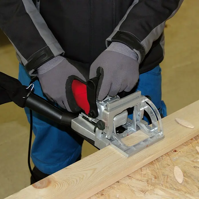 Einhell Engalletadora TC-BJ900 - 860 W, Profundidad de fresado: 14 mm - Una persona usa una ensambladora de galletas para procesar una tabla de madera, destacando la precisión de la herramienta.