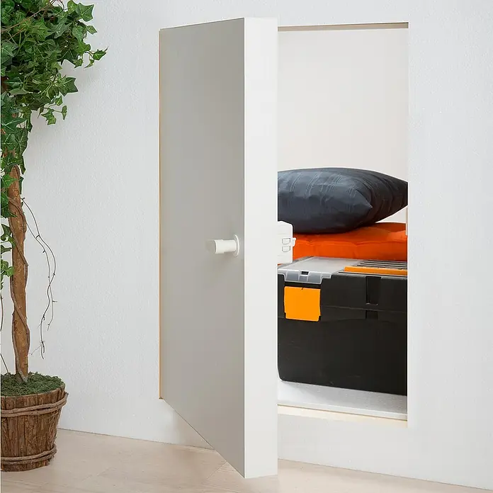 Dolle Kniestocktür - 56 x 80 cm - Eine teilweise geöffnete graue Tür gibt den Blick frei auf einen Abstellraum mit einer schwarzen Werkzeugkiste, einem orangefarbenen Tuch und einem Kissen.