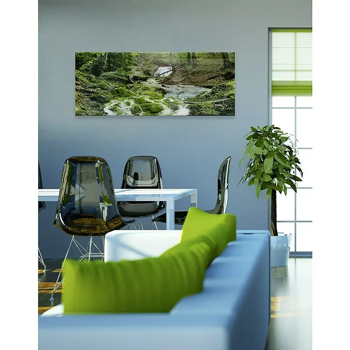 Glasbild - Mystic Ways, B x H: 80 x 30 cm - Ein Wohnraum mit einem Wandbild eines Waldbachs, das über einem weißen Esstisch und einem grünen Sofa hängt.