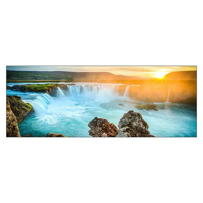 Glasbild - Colourful Waterfall, B x H: 80 x 30 cm - Eindrucksvolles Panorama eines Wasserfalls mit klarem, blauem Wasser und Felsen im Vordergrund bei Sonnenuntergang.