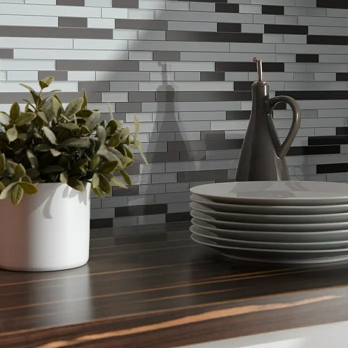 Mosaikfliese Mix XAM A891 - 29,8 x 33,8 cm, Grau/Schwarz, Matt - Ein graues Keramikfliesen-Wandbild mit Pflanzen, Tellern und einer grauen Ölflasche sorgt für eine elegante Küchendekoration.