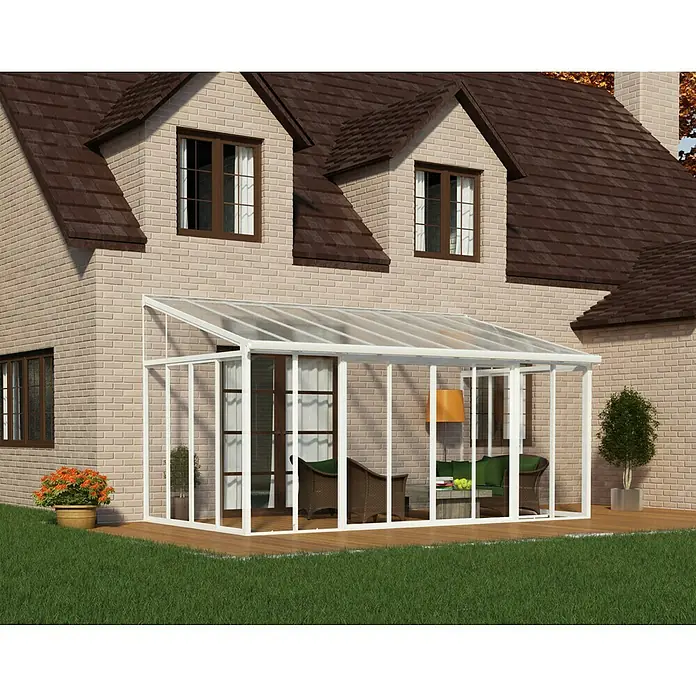 Palram – Canopia Porche acristalado San Remo - An x Pr x Al: 5,46 x 3 x 3,1 m, Blanco tráfico - Imagen de un invernadero de vidrio y acero conectado a una casa. El invernadero está amueblado con muebles de jardín.