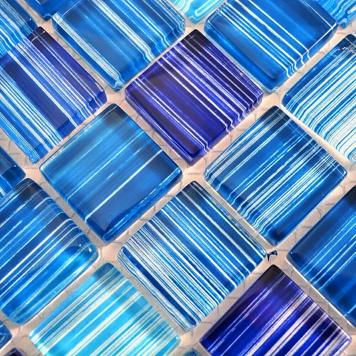 Mosaikfliese Quadrat Crystal XCM 8285 - 32,7 x 30,2 cm, Blau, Glänzend - Nahaufnahme von dekorativen blauen Glasmosaikfliesen mit weißen Streifen, die ein elegantes Muster für die Wandgestaltung bilden.