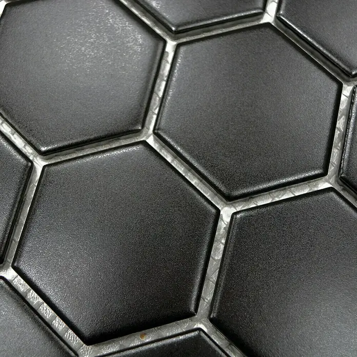 Mosaikfliese Hexagon Uni HX 095 - 32,5 x 28,1 cm, Schwarz, Matt - Nahaufnahme von schwarzen, sechseckigen Mosaikfliesen mit silberfarbenen Fugen, die ein modernes und stilvolles Design für Innenräume bieten.