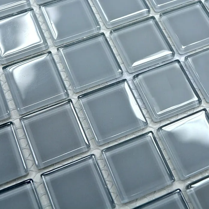 Mosaikfliese Quadrat Crystal Uni CM 4021 - 32,7 x 30,2 cm, Hellgrau, Glänzend - Nahaufnahme von quadratischen grauen Glasmosaikfliesen, die auf einem Blatt angeordnet sind und sich ideal für die Installation als stilvolle Wand- oder Bodengestaltung eignen.