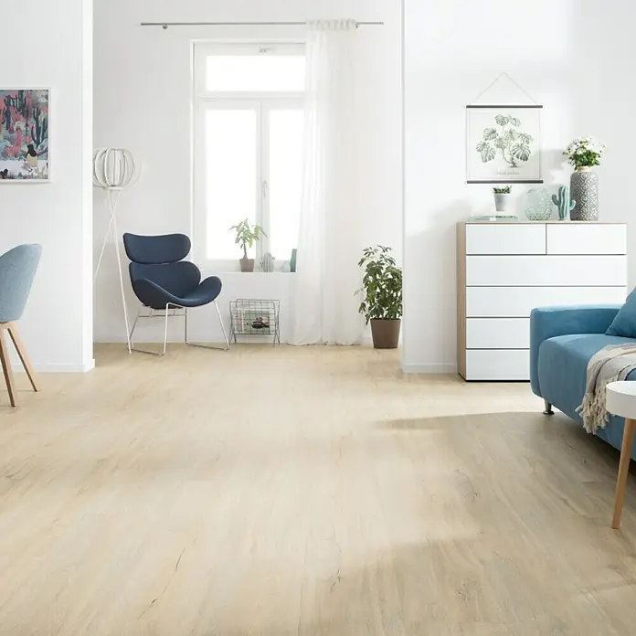Living by Haro Hydrostar Designboden Eiche Como1.282 x 235 x 6,5 mm, Landhausdiele, Eiche Como - Ein helles Wohnzimmer mit einem beigen Holzboden, einem blauen Sessel und einem passenden Sofa, das eine einladende Atmosphäre schafft.