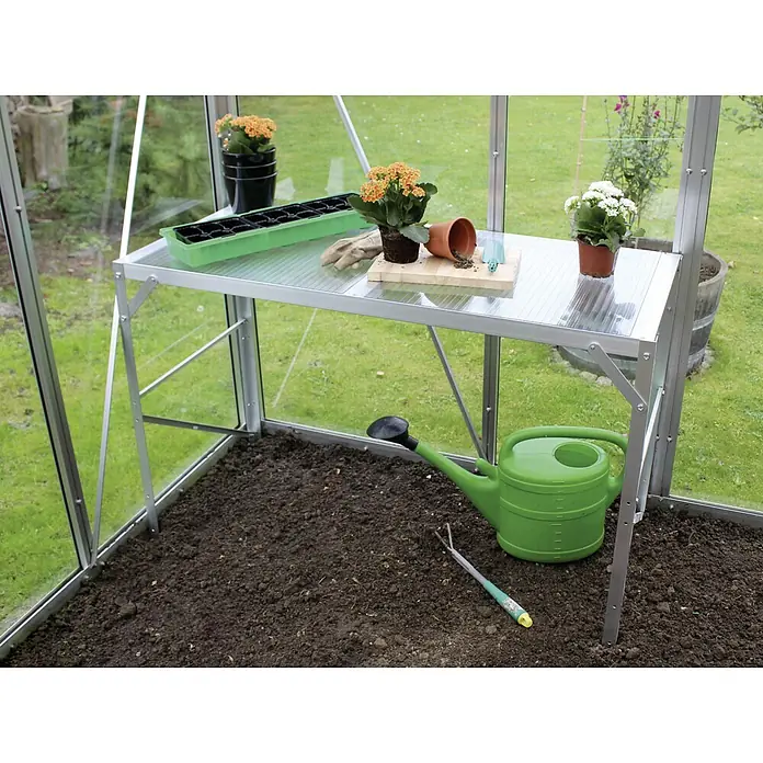 Vitavia Anzuchttisch II - 54 x 121 x 76 cm, Aluminium - Das Bild zeigt ein Gewächshaus mit einem Arbeitstisch, Pflanzen und einer Gießkanne, die zum Gärtnern einladen.