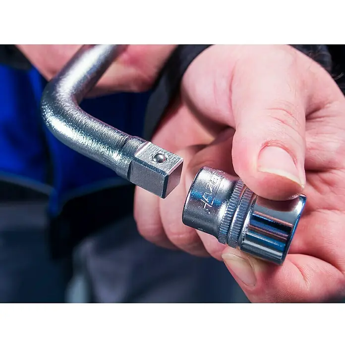 Hazet Teleskop-Radmutternschlüssel 772 - Teleskopierbar: 303 mm - 535 mm, Antriebsgröße: ½″ - Nahaufnahme eines Adapters und einer Stecknuss, die von einer Person gehalten werden, wahrscheinlich für Reparatur- oder Wartungsarbeiten.