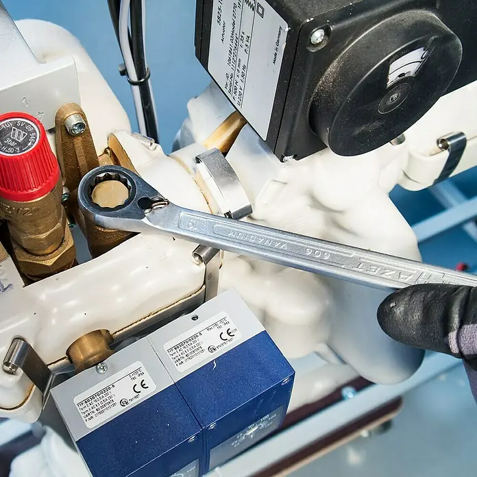 Hazet Knarren-Ringmaulschlüssel-Satz 606N/12 - 12 -tlg., Schlüsselweite: 8 mm - 19 mm - Nahaufnahme eines HAZET 606 Vanadium-Ringschlüssels, der an einer industriellen Anlage befestigt wird, mit Fokus auf Werkzeugdetails.