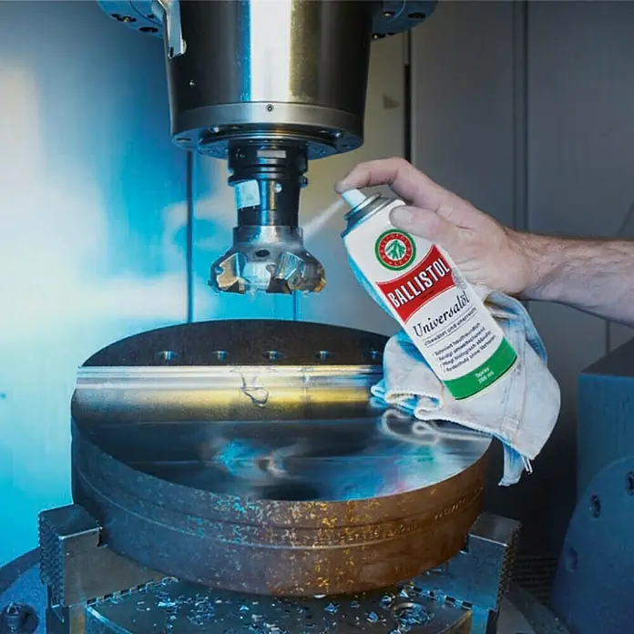 Ballistol Universalöl - 50 ml, Öl - Ein Mann sprüht Ballistol Universalöl auf eine Fräsmaschine. Das Universalöl schützt und pflegt die Maschine.
