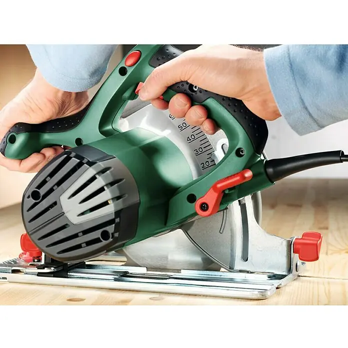 Bosch Handkreissäge PKS 66 AF - 1.600 W, 5.000 U/min - Nahaufnahme einer grünen Bosch Kreissäge mit rotem Griff und Messskala, die auf einem Holztisch verwendet wird.