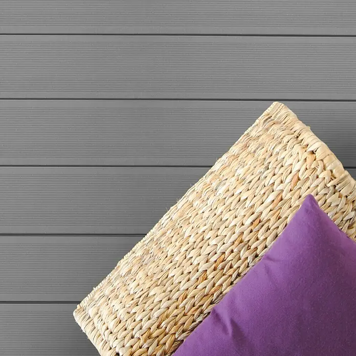Kovalex WPC-Terrassendiele Massiv strukturo nach Maß - 300 x 14,5 x 2 cm, Grau - Nahaufnahme eines geflochtenen Korbs mit einem violetten Kissen, der Textur und Komfort für ein gemütliches Ambiente bietet.