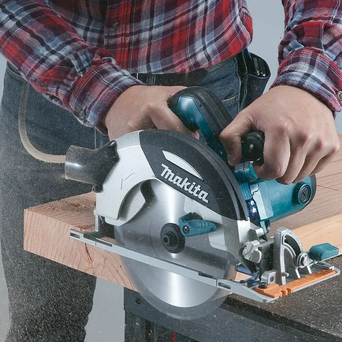 Makita Handkreissäge HS7101J1 - 1.400 W, Durchmesser Sägeblatt: 190 mm - Nahaufnahme einer Makita-Kreissäge in Aktion, bedient von einer Person in Arbeitskleidung. Das Werkzeug schneidet Holz präzise.