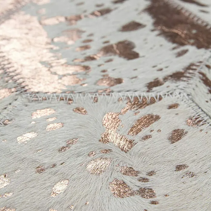 Kayoom Lederteppich Dazzle 200Elfenbein/Chrom, 230 x 160 cm, 100 % Leder - Nahaufnahme eines stilvollen Teppichs mit Kuhfellmuster und goldenen Akzenten, der jedem Raum einen Hauch von Luxus verleiht.