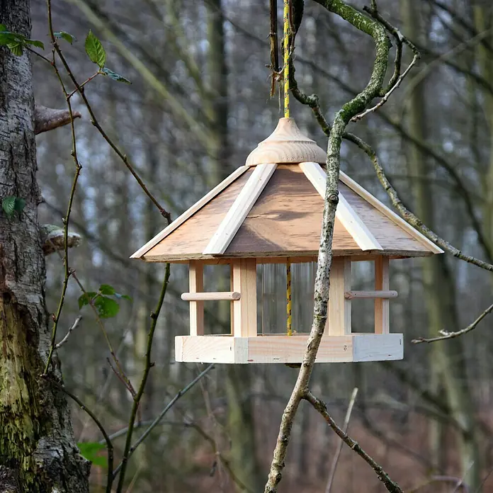 Dobar Sechseck-Vogelfutterhaus - 35 x 35 x 29 cm, Mit Silo - Ein hölzernes Vogelhaus hängt an einem Baum mit einem gelben Seil. Das Vogelhaus hat ein Dach und eine Plattform für Vögel.