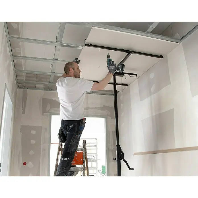 Rikta Plattenlift - 40 kg, Höhenverstellung: 155 cm - 300 cm - Ein Handwerker montiert eine Deckenplatte mit einem Werkzeuglift. Der Trockenbau ist in vollem Gange, um das Haus zu verschönern.