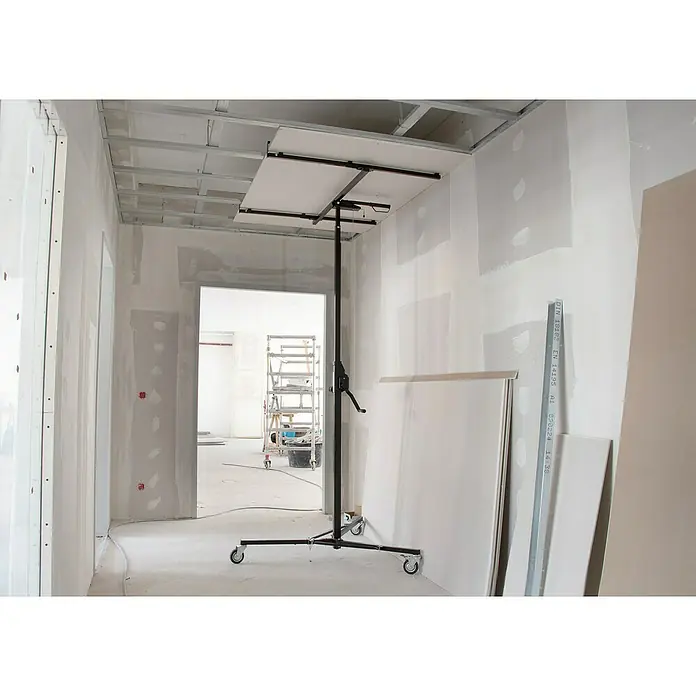 Rikta Plattenlift - 40 kg, Höhenverstellung: 155 cm - 300 cm - Innenaufnahme eines Raumes im Rohbau mit Gipskartonplatten-Hebegerät zur Deckenmontage und Baumaterialien.