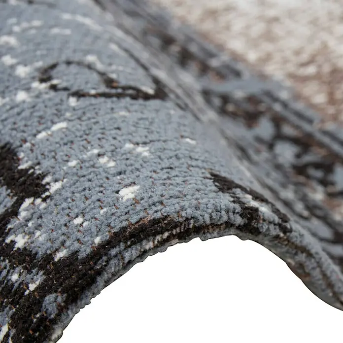 Kayoom Flachgewebeteppich JacquardBraun, 170 x 120 cm, 100 % Baumwolle - Nahaufnahme einer grauen Teppichrolle mit abstraktem Muster, die Textur und Design hervorhebt.