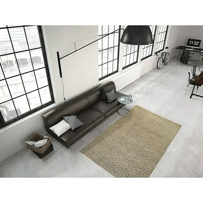 Kayoom Flachgewebeteppich Cocktail 300 - Beige/Braun, 170 x 120 cm, 100% Baumwolle - Ein Teppich mit geometrischem Rautenmuster in Beige und Braun ziert einen modern eingerichteten Wohnbereich mit Ledercouch und großen Fenstern.