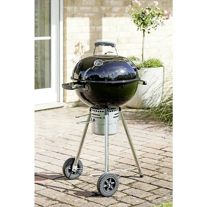 Kingstone Kugelgrill Bullet 47 - Durchmesser Grillfläche: 47 cm, Schwarz - Nahaufnahme eines runden, schwarzen Kugelgrills mit silbernen Beinen und Rädern, der auf einer gepflasterten Terrasse steht.