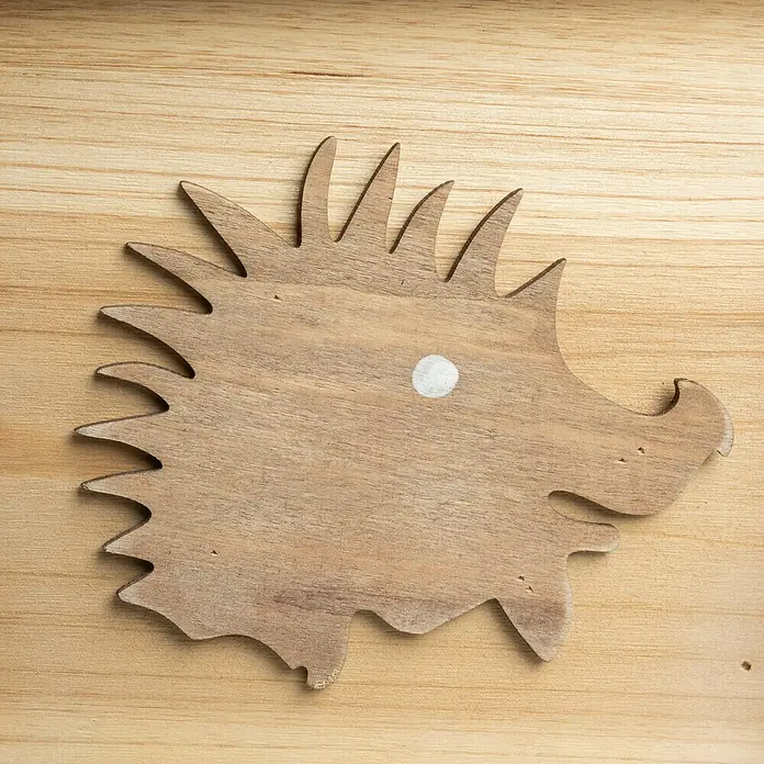 Windhager Igelhaus Bausatz - Holz, Braun - Holzförmiger Igel mit einem weißen Punkt als Auge auf einem Holzhintergrund.