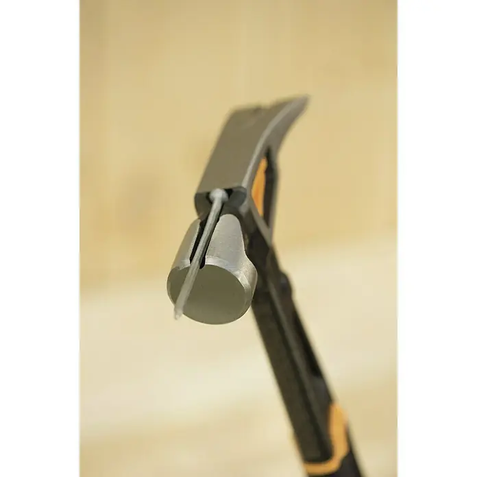 Fiskars Universalhammer M - Gewicht Kopf: 450 g, Länge: 340 mm - Nahaufnahme eines Zimmermannshammers mit Nagel im magnetischen Nagelhalter vor beigem Hintergrund.