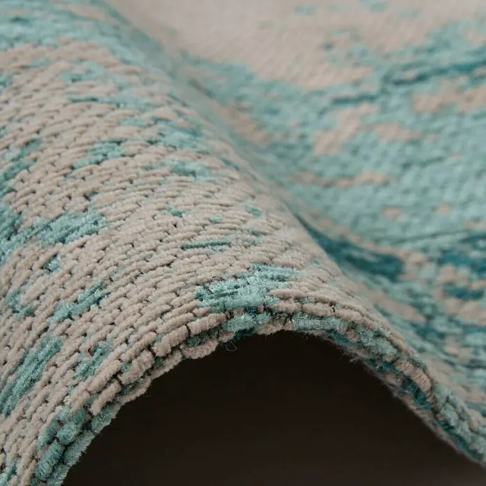Kayoom Flachgewebeteppich Select 275 - Türkis, 170 x 120 cm, 50% Baumwolle, 50% Polyester Chenille - Nahaufnahme eines abstrakten Teppichs mit blauen und beigen Farbtönen, der eine weiche Textur und hochwertige Verarbeitung zeigt.