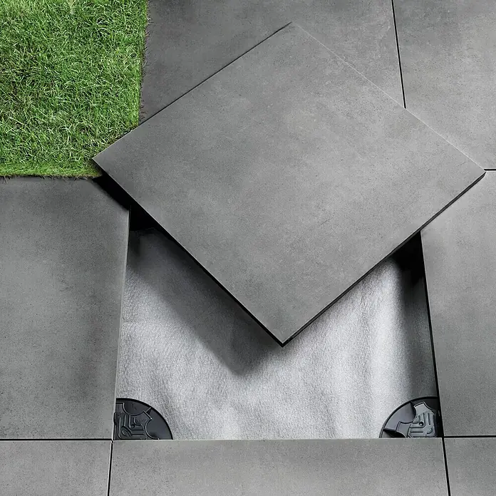 Art-Tec by Palazzo Terrassenfliese - 60 x 60 x 2 cm, Graphit, Matt - Bild von Outdoor-Fliesen mit Unterkonstruktion und Kunstrasen. Die Fliesen sind aus grauem Beton und wirken sehr modern und stilvoll.