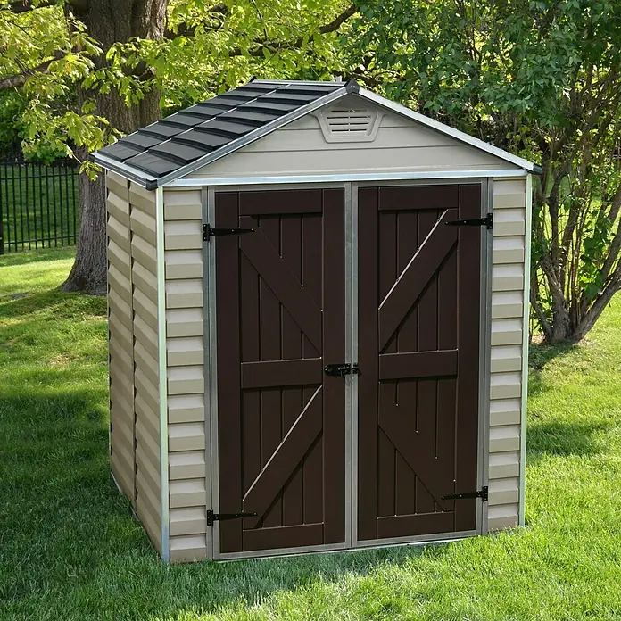 Palram – Canopia Gerätehaus Skylight 6x5 Tan - Außenmaß inkl. Dachüberstand (B x T): 185 x 154 cm, Kunststoff, Beige/Braun - Ein beiges Gerätehaus mit braunen Türen und einem grauen Dach steht im Garten. Das Gerätehaus bietet Stauraum für Gartengeräte und Werkzeuge.