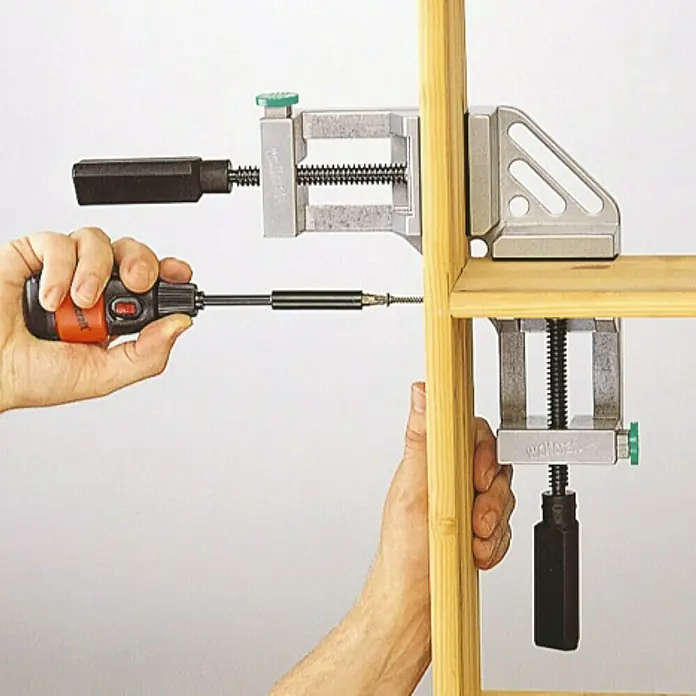 Sargento - Anchura de sujeción: 65 mm - Mordaza de esquina en uso, asegurando madera para la construcción de muebles con un destornillador. Ideal para juntas de esquina precisas y estables.