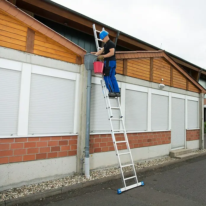 Krause Stabilo Schiebeleiter - Anzahl Tritte: 18 Stk., Arbeitshöhe: 5,25 m, Aluminium - Mann reinigt Dachrinne mit Teleskopleiter und Eimer. Die Leiter ist robust und für Arbeiten in der Höhe geeignet.