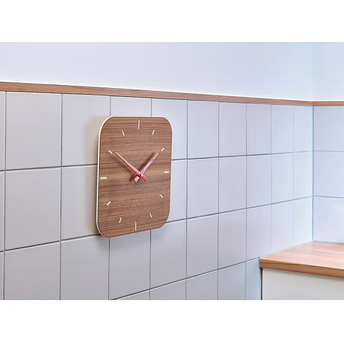 Tesa Clavo adhesivo - Blanco, Carga soportada: 2 kg, 2 ud., Azulejos - Un moderno reloj de pared de madera con manecillas rosas cuelga de una pared de azulejos. Añade un toque de elegancia y funcionalidad.