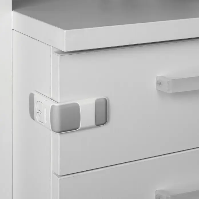Inofix Cierre para muebles 5103-2- - Blanco/gris, Tipo de montaje: Pegado - Cierre de seguridad infantil adjunto a una cómoda blanca. El cierre está colocado en la esquina del cajón y impide que se abra.