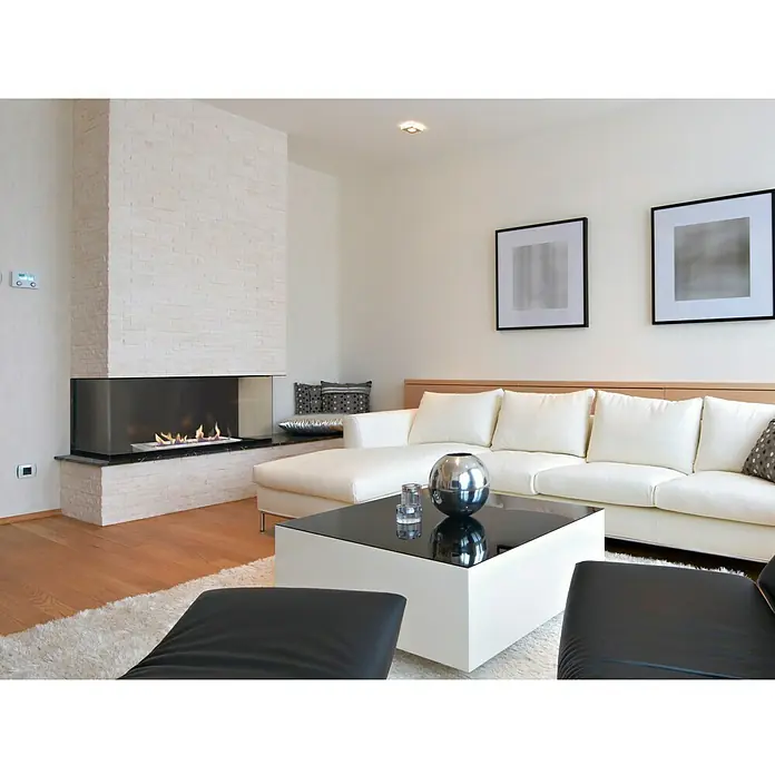 Purline Bloque de combustión F96150 - 1.500 x 200 x 90 mm, Acero inoxidable - La imagen muestra una sala de estar moderna con una chimenea elegante, un sofá blanco y una mesa de centro negra, creando un ambiente armonioso.
