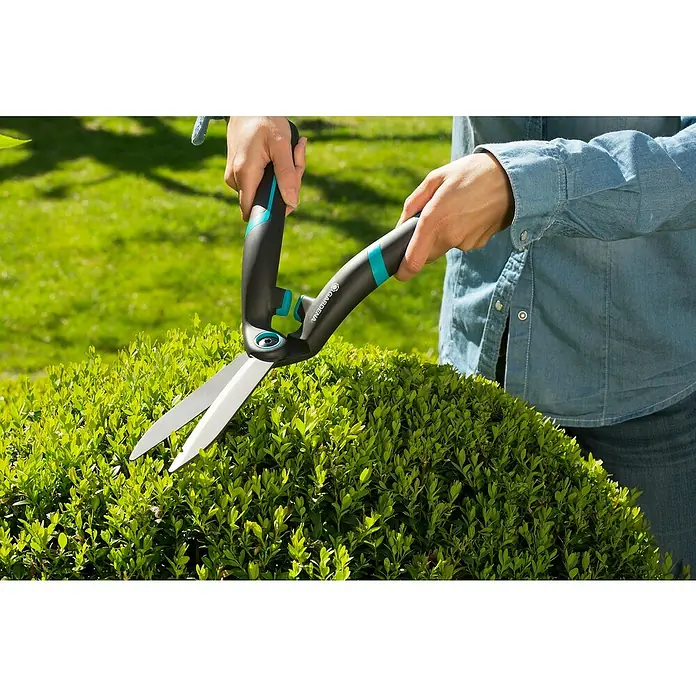 Gardena Tijeras de podar manuales PrecisionCut - Largo: 475 mm - Primer plano de una persona podando un arbusto con tijeras de jardinería Gardena, centrado en la herramienta y su uso.