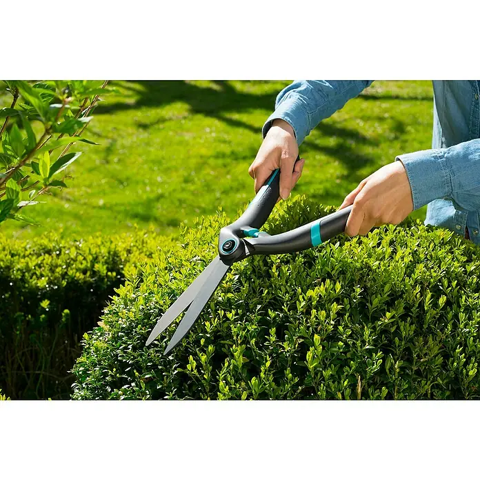Gardena Tijeras de podar manuales PrecisionCut - Largo: 475 mm - Una persona recorta un seto con tijeras Gardena, mostrando las cuchillas afiladas y el mango ergonómico.