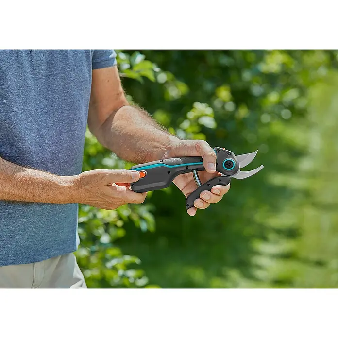 Gardena Tijeras de podar de batería AssistCut - L x An x Al: 270 x 70 x 30 mm, Grosor de rama máx.: 25 mm - Primer plano de una persona que sostiene unas tijeras de podar inalámbricas Gardena, diseñadas para cortar sin esfuerzo ramas y ramitas en el jardín.
